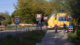 804336 Gezicht op de gesloten spoorwegovergang in de Mereveldseweg te Utrecht, met een passerende trein.